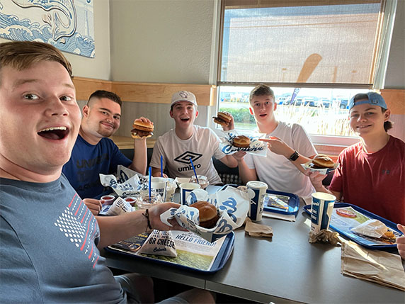 A group of boys smile with CurderBurgers in hand.